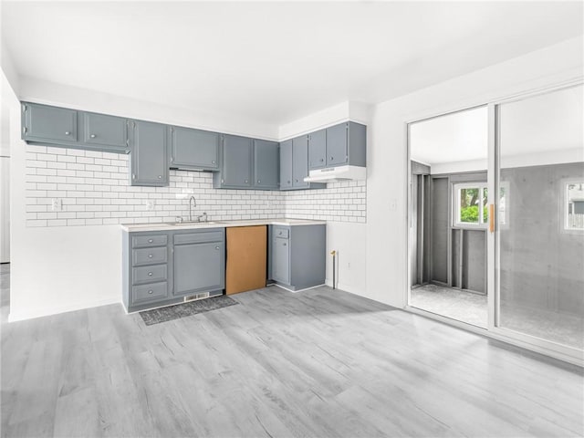 25 Martha Rd, East Providence, RI 02916 - kitchen with light wood-style floors, backsplash, under cabinet range hood, light countertops, and gray cabinets