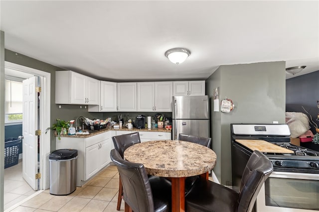 313 Branch Ave, Providence, RI 02904 - kitchen with appliances with stainless steel finishes, white cabinets, light tile patterned floors, and light stone countertops