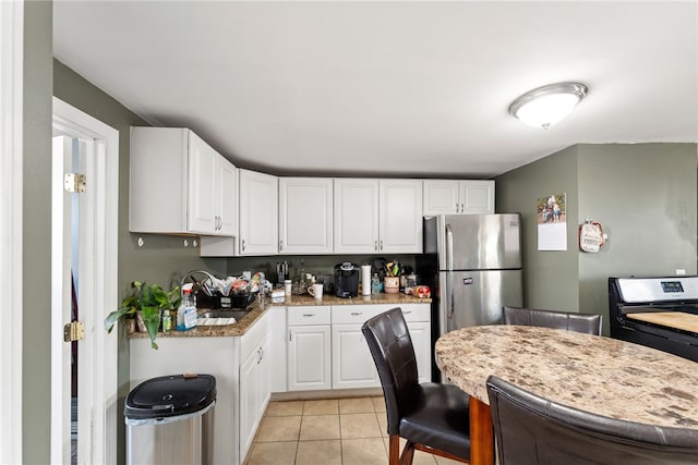 313 Branch Ave, Providence, RI 02904 - kitchen featuring white cabinetry, freestanding refrigerator, light tile patterned flooring, light countertops, and black range with gas stovetop