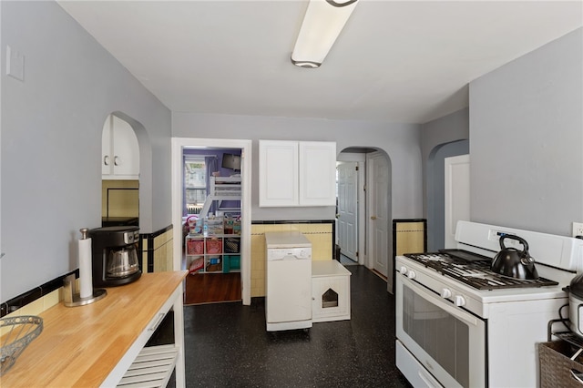 313 Branch Ave, Providence, RI 02904 - kitchen featuring white range with gas stovetop, arched walkways, white cabinetry, and light countertops