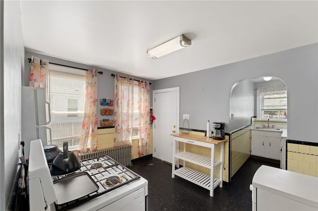 313 Branch Ave, Providence, RI 02904 - kitchen featuring white appliances, radiator heating unit, light countertops, arched walkways, and a wainscoted wall
