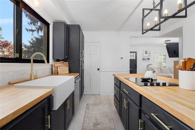 110 Spofford Ave, Warwick, RI 02888 - kitchen with butcher block counters, black electric stovetop, dark cabinetry, light wood finished floors, and decorative light fixtures