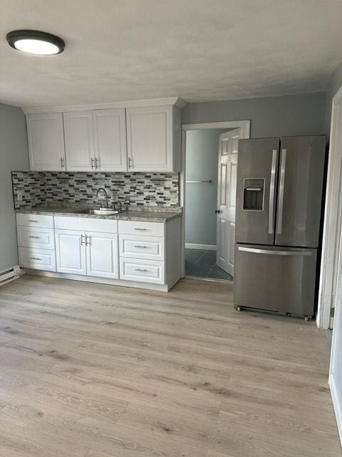 25 School St, West Warwick, RI 02893 - kitchen with stainless steel fridge with ice dispenser, tasteful backsplash, light wood finished floors, white cabinetry, and baseboard heating