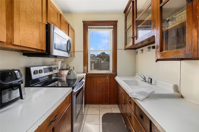 105 Overland Ave, Cranston, RI 02910 - kitchen with appliances with stainless steel finishes, light countertops, brown cabinets, light tile patterned floors, and glass insert cabinets