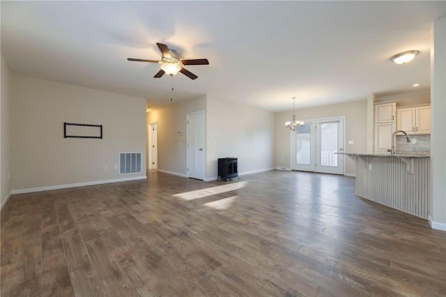 109 Chickadee Ln, South Kingstown, RI 02879 - unfurnished living room with a wood stove, a ceiling fan, dark wood-type flooring, and a chandelier