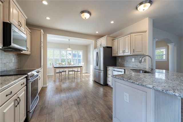 109 Chickadee Ln, South Kingstown, RI 02879 - kitchen featuring appliances with stainless steel finishes, ornate columns, dark wood finished floors, tasteful backsplash, and light stone countertops