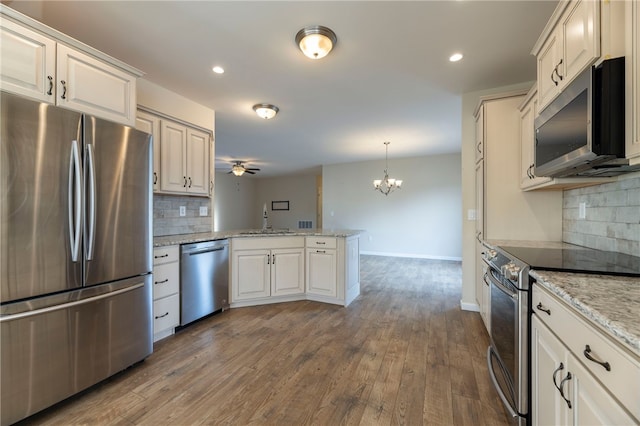 109 Chickadee Ln, South Kingstown, RI 02879 - kitchen featuring stainless steel appliances, a peninsula, a chandelier, tasteful backsplash, and recessed lighting