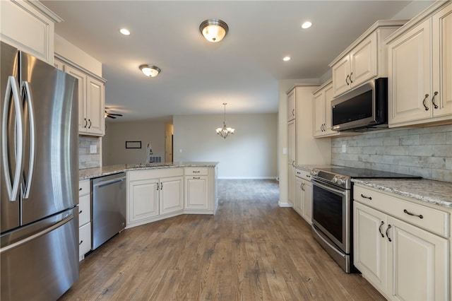 109 Chickadee Ln, South Kingstown, RI 02879 - kitchen with appliances with stainless steel finishes, a peninsula, a chandelier, decorative backsplash, and wood finished floors