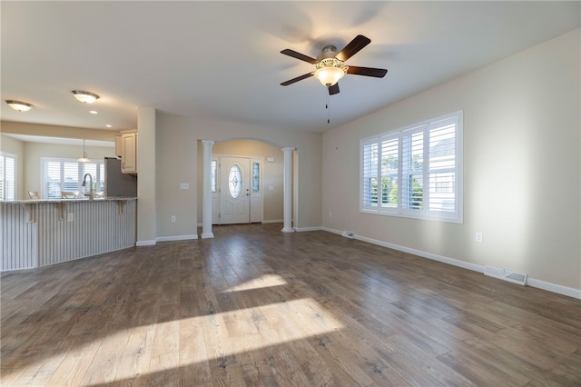 109 Chickadee Ln, South Kingstown, RI 02879 - unfurnished living room with decorative columns, a ceiling fan, dark wood-style flooring, and arched walkways