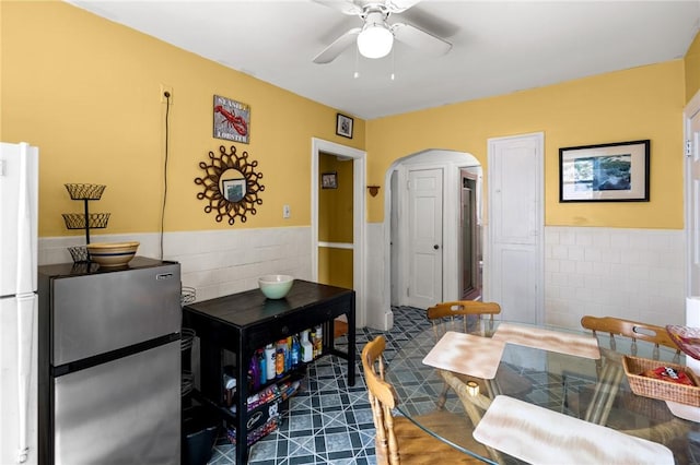 41 Higgins Ave, Providence, RI 02908 - dining room featuring tile walls, arched walkways, a wainscoted wall, and ceiling fan
