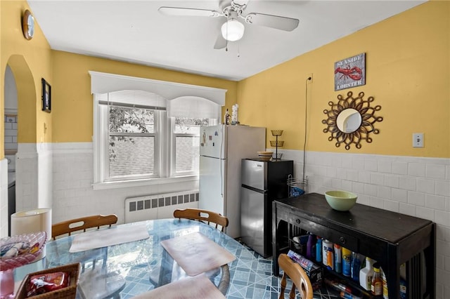41 Higgins Ave, Providence, RI 02908 - dining space with radiator, tile walls, a ceiling fan, a wainscoted wall, and arched walkways