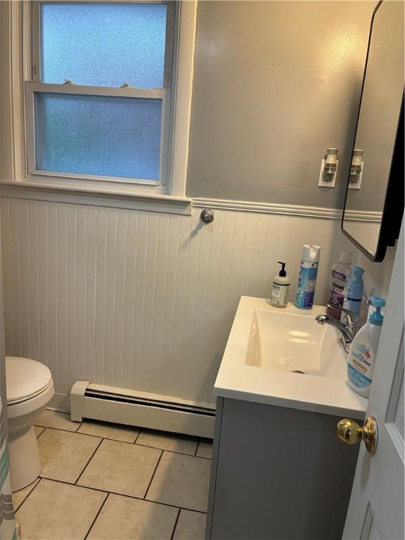 121 Murray St, Providence, RI 02909 - half bathroom with baseboard heating, vanity, tile patterned flooring, and wainscoting
