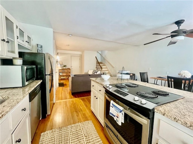 446 Bellevue Ave Unit 6, Newport, RI 02840 - kitchen with stainless steel appliances, light wood-style floors, ceiling fan, white cabinetry, and glass insert cabinets