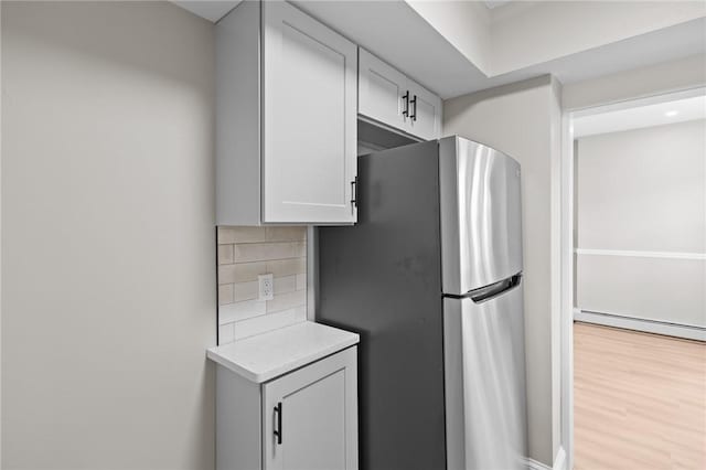 233 Waterman Ave, East Providence, RI 02914 - kitchen with freestanding refrigerator, a baseboard radiator, backsplash, light countertops, and light wood-type flooring