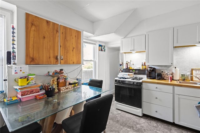 233 Waterman Ave, East Providence, RI 02914 - kitchen with white gas range oven, white cabinets, a kitchen breakfast bar, tasteful backsplash, and light countertops
