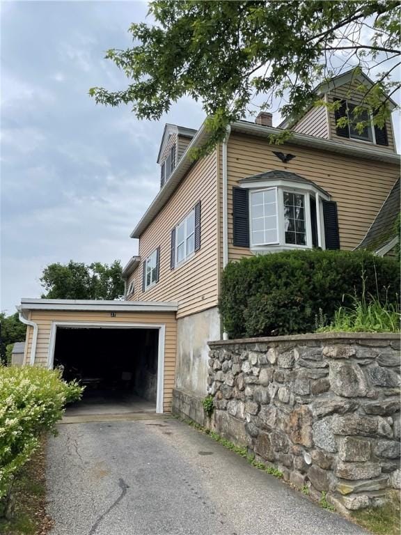 37 Kermit St, Woonsocket, RI 02895 - view of property exterior with asphalt driveway, a chimney, and an attached garage