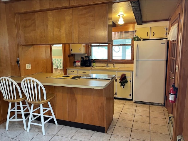 37 Kermit St, Woonsocket, RI 02895 - kitchen featuring freestanding refrigerator, light countertops, a peninsula, light tile patterned floors, and wooden walls