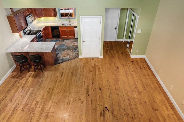 1 Tupperware Dr Unit 231, North Smithfield, RI 02896 - kitchen with appliances with stainless steel finishes, light wood-style floors, a kitchen bar, and a peninsula