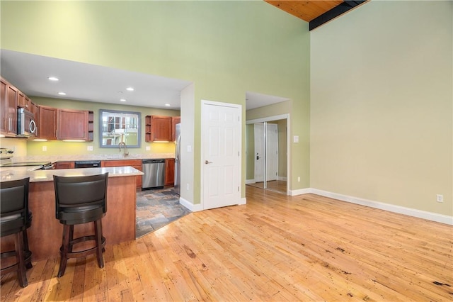1 Tupperware Dr Unit 231, North Smithfield, RI 02896 - kitchen with stainless steel appliances, a towering ceiling, light wood finished floors, a kitchen bar, and light countertops