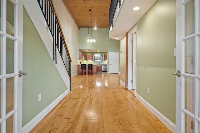 1 Tupperware Dr Unit 231, North Smithfield, RI 02896 - corridor featuring light wood-style floors, french doors, a towering ceiling, a chandelier, and stairs