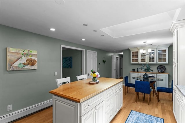 55 Atherton Rd, East Greenwich, RI 02818 - kitchen with a baseboard heating unit, a chandelier, light wood-style flooring, wood counters, and white cabinetry