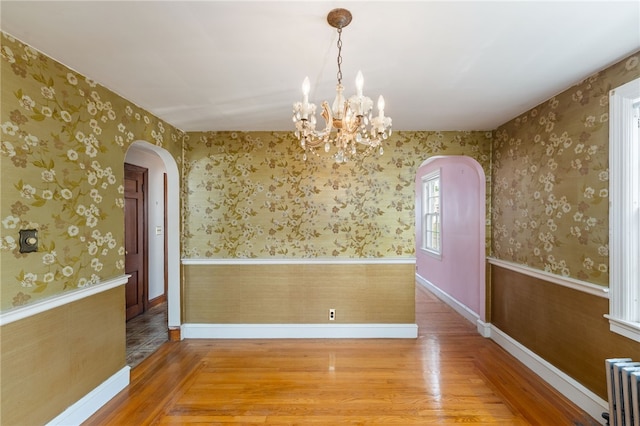 53 Overland Ave, Cranston, RI 02910 - unfurnished dining area with radiator, arched walkways, wood finished floors, a chandelier, and wainscoting
