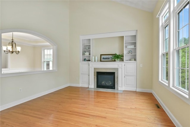 99 Preservation Way S, Kingstown, RI 02879 - unfurnished living room featuring plenty of natural light, light wood finished floors, a chandelier, a fireplace with flush hearth, and high vaulted ceiling