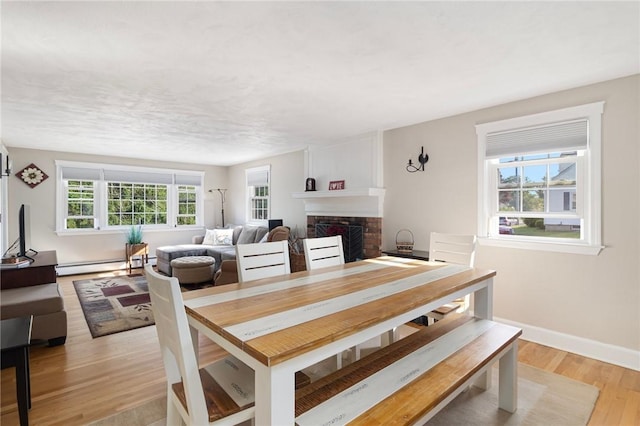 1 Adelaide Ave, Bristol, RI 02809 - dining area with baseboard heating, light wood-type flooring, and a fireplace