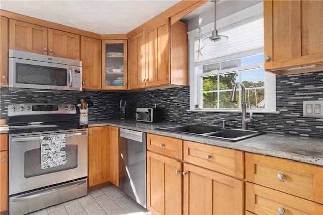 1 Adelaide Ave, Bristol, RI 02809 - kitchen featuring appliances with stainless steel finishes, decorative backsplash, glass insert cabinets, brown cabinetry, and hanging light fixtures