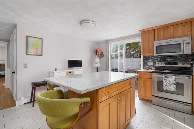 1 Adelaide Ave, Bristol, RI 02809 - kitchen with appliances with stainless steel finishes, a kitchen island, light stone counters, tasteful backsplash, and light wood-style flooring