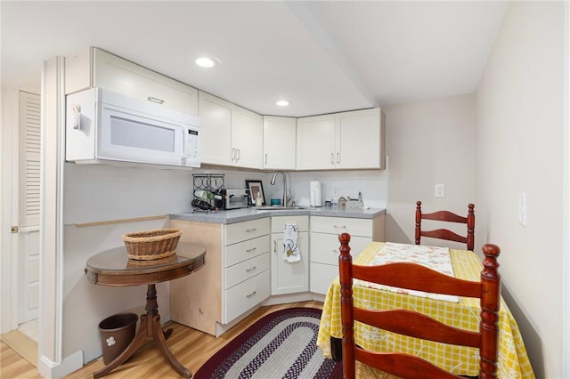 1 Adelaide Ave, Bristol, RI 02809 - kitchen with white microwave, light wood-type flooring, decorative backsplash, white cabinetry, and recessed lighting