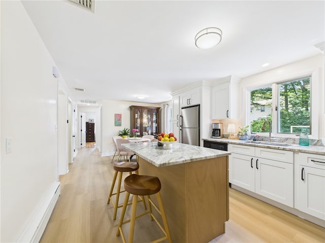 65 Bayberry Ln, East Greenwich, RI 02818 - kitchen featuring freestanding refrigerator, light wood finished floors, a center island, a baseboard radiator, and a breakfast bar