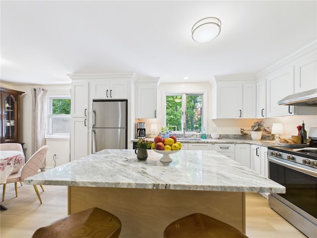 65 Bayberry Ln, East Greenwich, RI 02818 - kitchen featuring appliances with stainless steel finishes, light wood finished floors, white cabinets, light stone countertops, and a center island