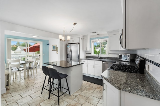 32 Waterman Ave, Johnston, RI 02919 - kitchen with stainless steel appliances, a center island, white cabinetry, a kitchen bar, and a chandelier