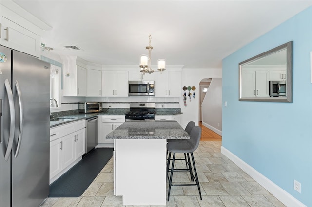 32 Waterman Ave, Johnston, RI 02919 - kitchen with appliances with stainless steel finishes, arched walkways, white cabinetry, and a center island