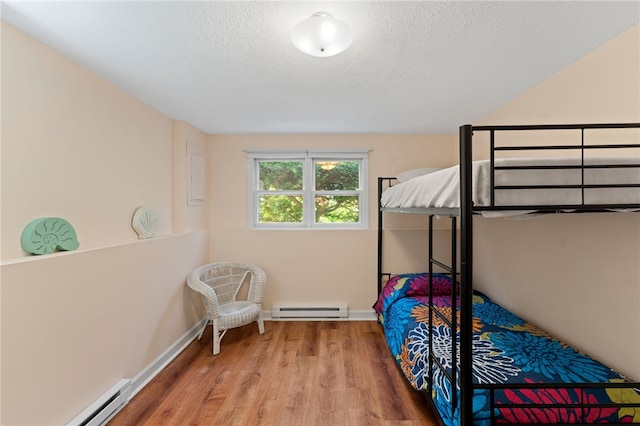 143 Juniper Rd, South Kingstown, RI 02879 - bedroom featuring a baseboard heating unit, wood finished floors, and a textured ceiling