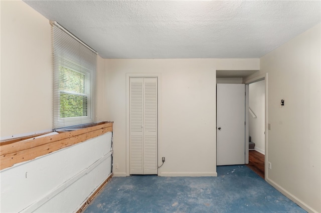 143 Juniper Rd, South Kingstown, RI 02879 - unfurnished bedroom featuring a textured ceiling, a closet, and unfinished concrete floors