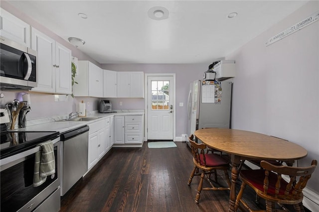 100 Pine Grove St, East Providence, RI 02916 - kitchen featuring stainless steel appliances, light countertops, dark wood-style flooring, white cabinets, and a baseboard heating unit