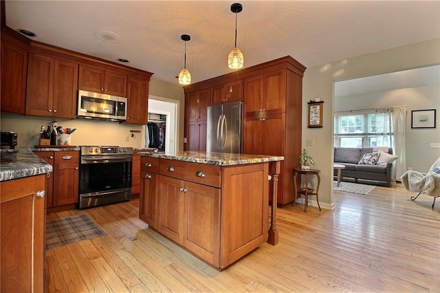10 N Dr, Westerly, RI 02891 - kitchen with stainless steel appliances, a kitchen island, light wood-style floors, dark stone countertops, and decorative light fixtures