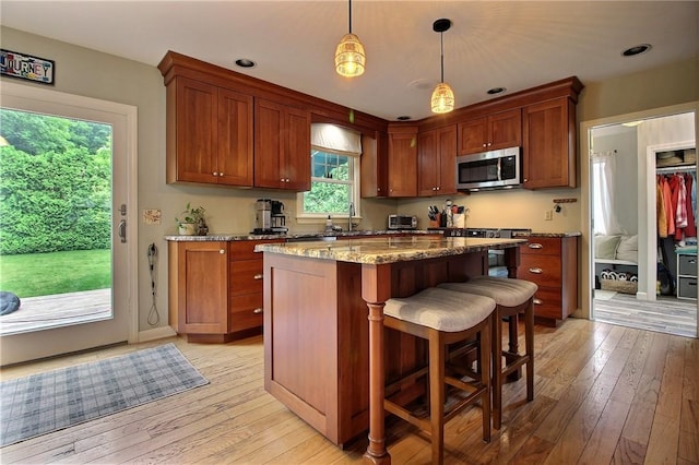 10 N Dr, Westerly, RI 02891 - kitchen with stainless steel microwave, light wood-style floors, dark stone countertops, a kitchen island, and decorative light fixtures