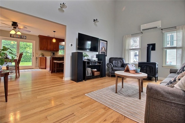 10 N Dr, Westerly, RI 02891 - living room featuring a wood stove, a wall mounted AC, a ceiling fan, light wood-type flooring, and a towering ceiling