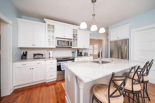 40 Vine St, East Greenwich, RI 02818 - kitchen featuring stainless steel appliances, wood finished floors, tasteful backsplash, a breakfast bar area, and glass insert cabinets