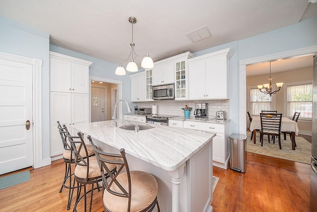 40 Vine St, East Greenwich, RI 02818 - kitchen with stainless steel appliances, a chandelier, light wood-type flooring, and white cabinetry