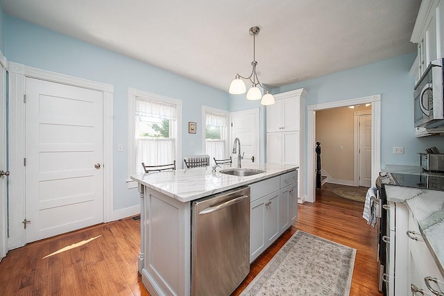 40 Vine St, East Greenwich, RI 02818 - kitchen featuring appliances with stainless steel finishes, wood finished floors, a center island with sink, and light stone counters