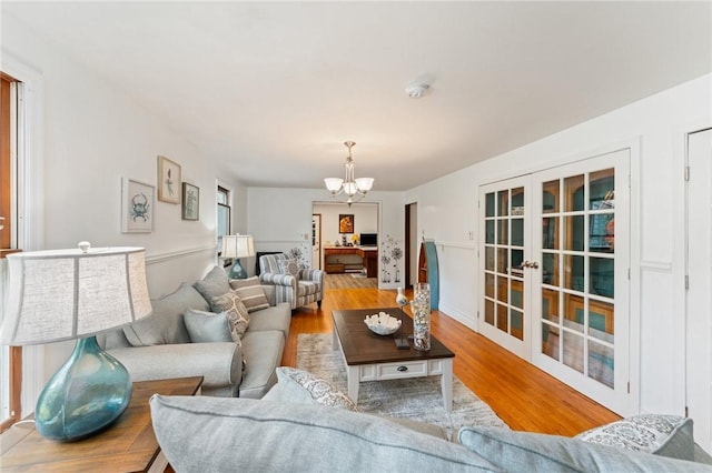 1451 Ministerial Rd, South Kingstown, RI 02879 - living room featuring french doors, a chandelier, and wood finished floors