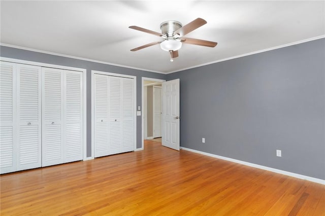 9 Esek Hopkins Rd, Scituate, RI 02857 - unfurnished bedroom with multiple closets, light wood-style floors, ornamental molding, and ceiling fan