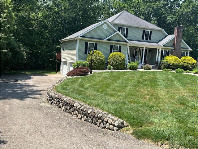 14 Piezzo Dr, Westerly, RI 02891 - view of front facade with covered porch, asphalt driveway, an attached garage, a chimney, and a front lawn