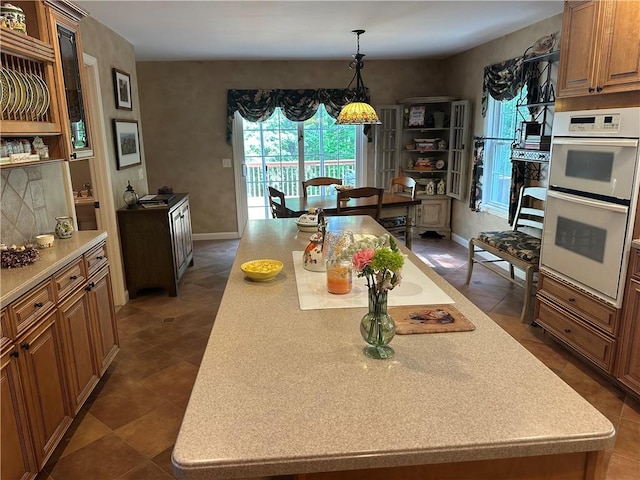 14 Piezzo Dr, Westerly, RI 02891 - kitchen with double oven, a center island, brown cabinetry, light countertops, and pendant lighting