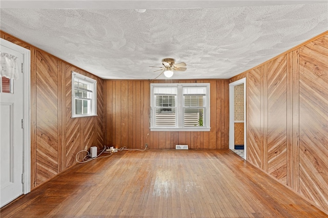 34 Tilden Ave, Warwick, RI 02888 - empty room with hardwood / wood-style floors, a ceiling fan, wooden walls, and a textured ceiling