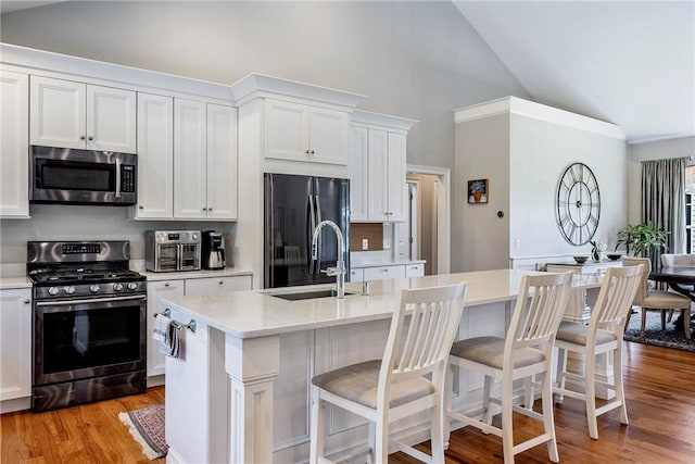 42 Aubin St, Seekonk, MA 02771 - kitchen with appliances with stainless steel finishes, high vaulted ceiling, white cabinets, light wood-type flooring, and a kitchen breakfast bar